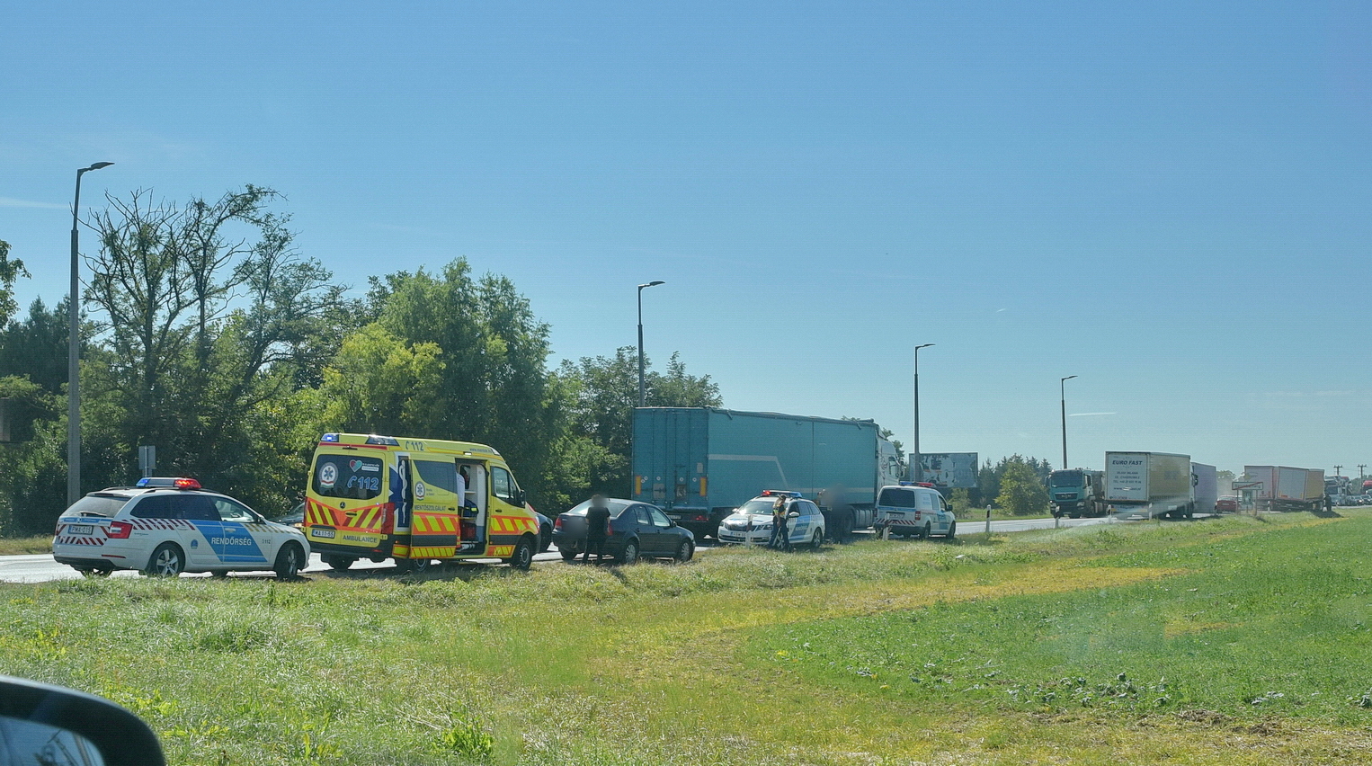 Álló Volkswagennek hajtott zöld jelzésnél elinduló Volvo kamion a 86-os főúton